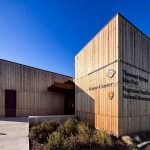 Modern wooden visitor center building at Thousand Springs State Park, with clear signage and a landscaped entrance under a bright blue sky. Hagerman, ID